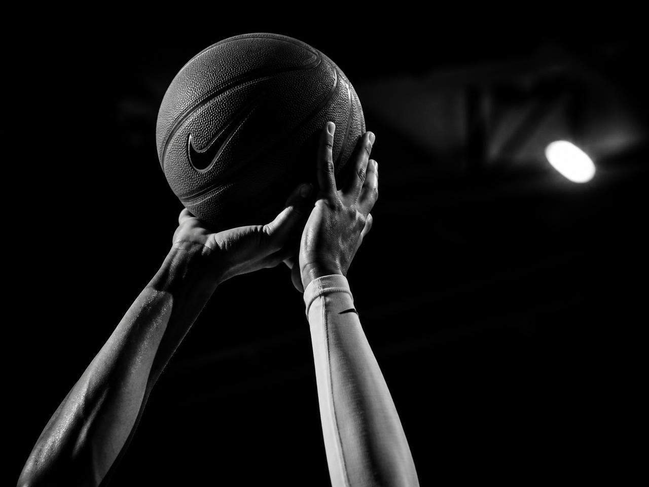 Close detail of a player's shooting form in a dark gym